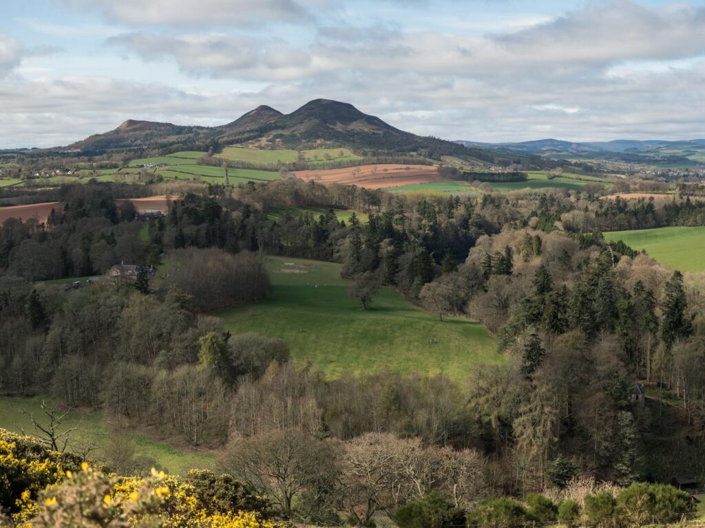 A beautiful aerial view of Scotland's Eildon Hills with lush green countryside and trees.