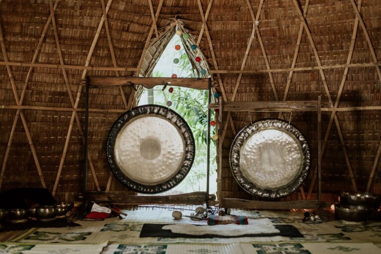 Interior view of a bamboo hut featuring traditional gongs used for sound healing and meditation.