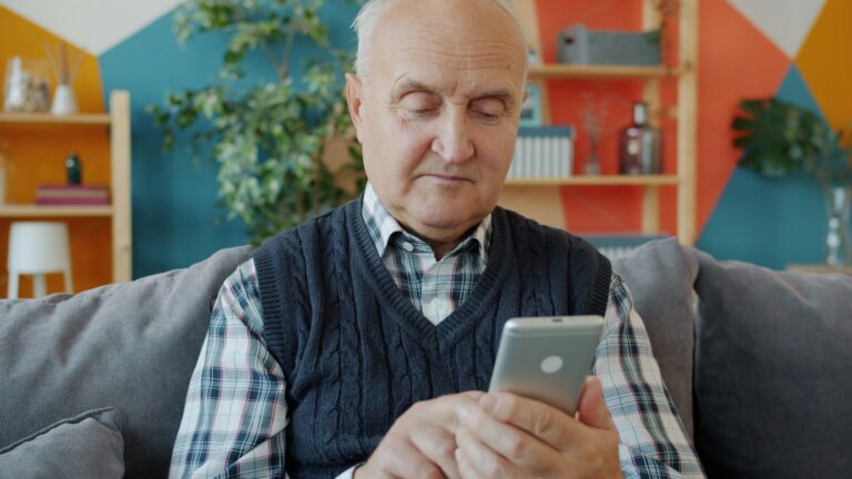 Elderly man using a smartphone on a couch
