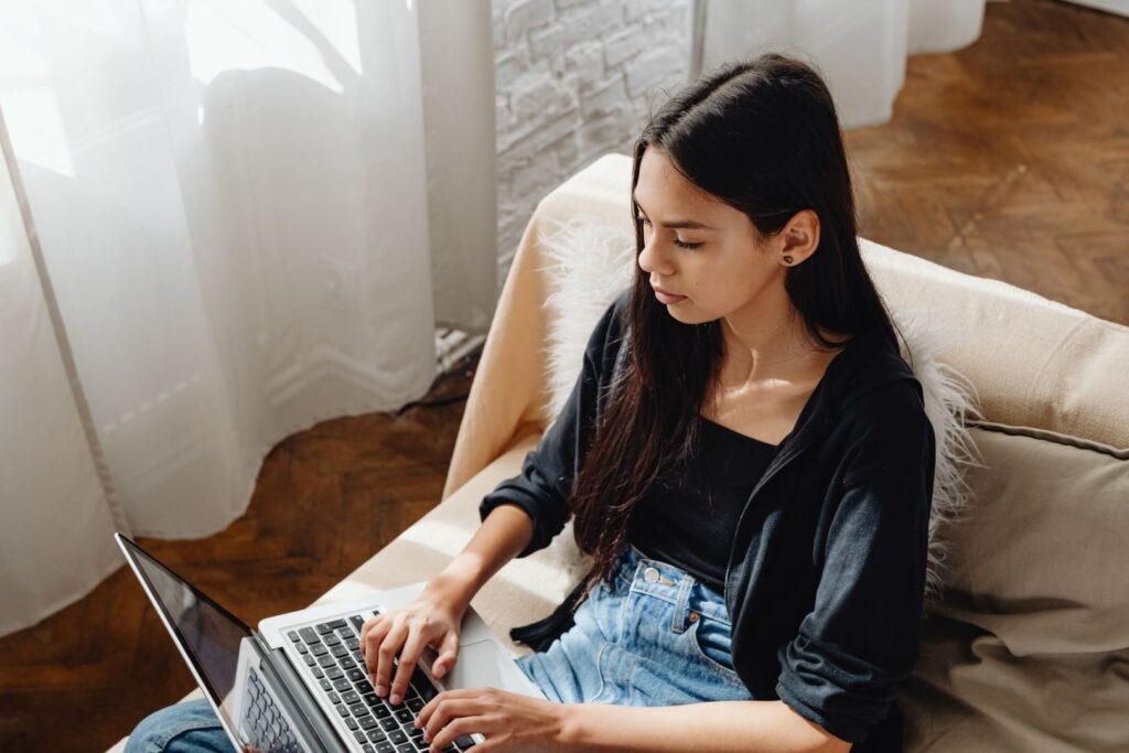 A woman focused on work while using a laptop at home, embodying the remote work lifestyle.