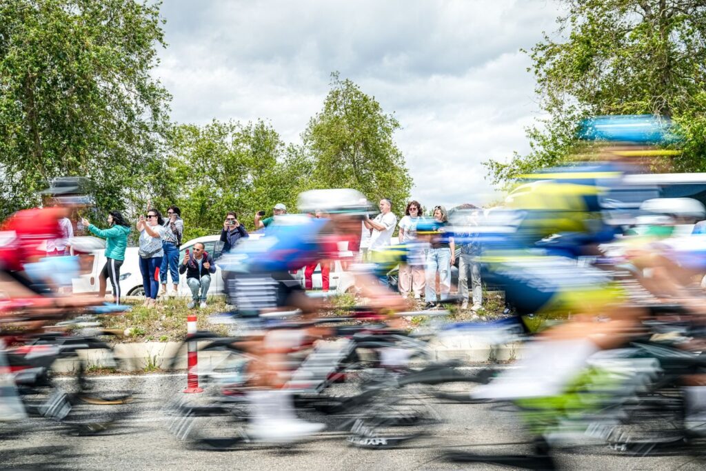 Blurred cyclists racing with onlookers in Mersin, Türkiye during a vibrant day event.