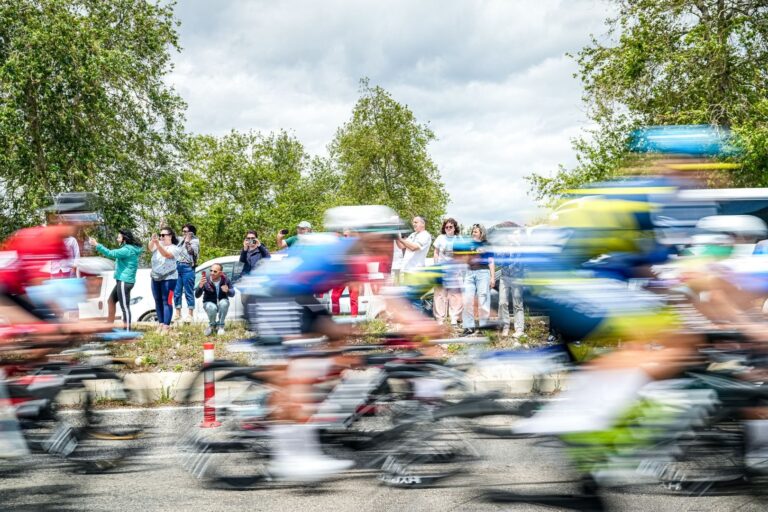 Blurred cyclists racing with onlookers in Mersin, Türkiye during a vibrant day event.