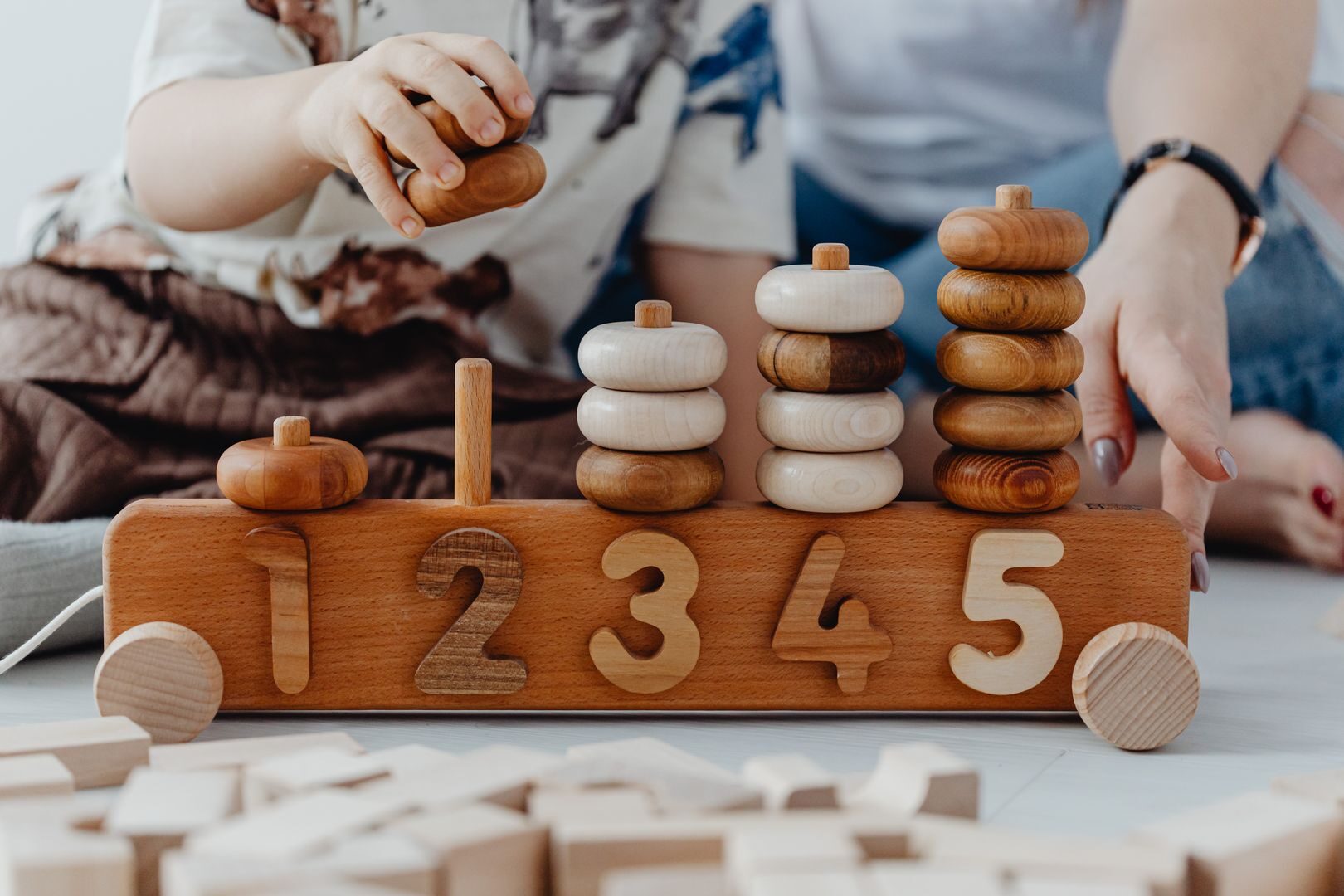 A child and adult playing with wooden number toys, enhancing learning and coordination skills.