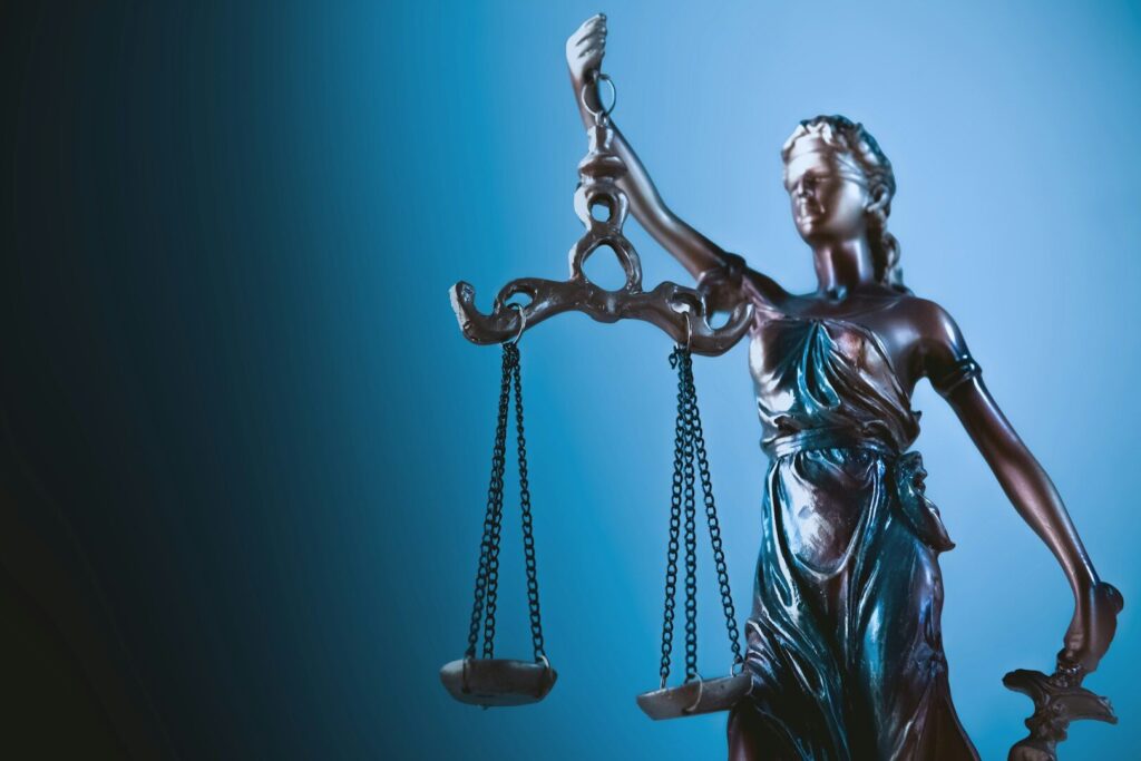 Statue of justice holding scales against blue background